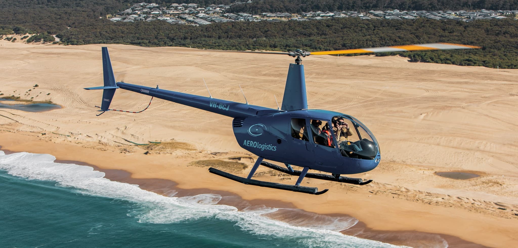 Helicopter flying low along sandy beach coastline tour