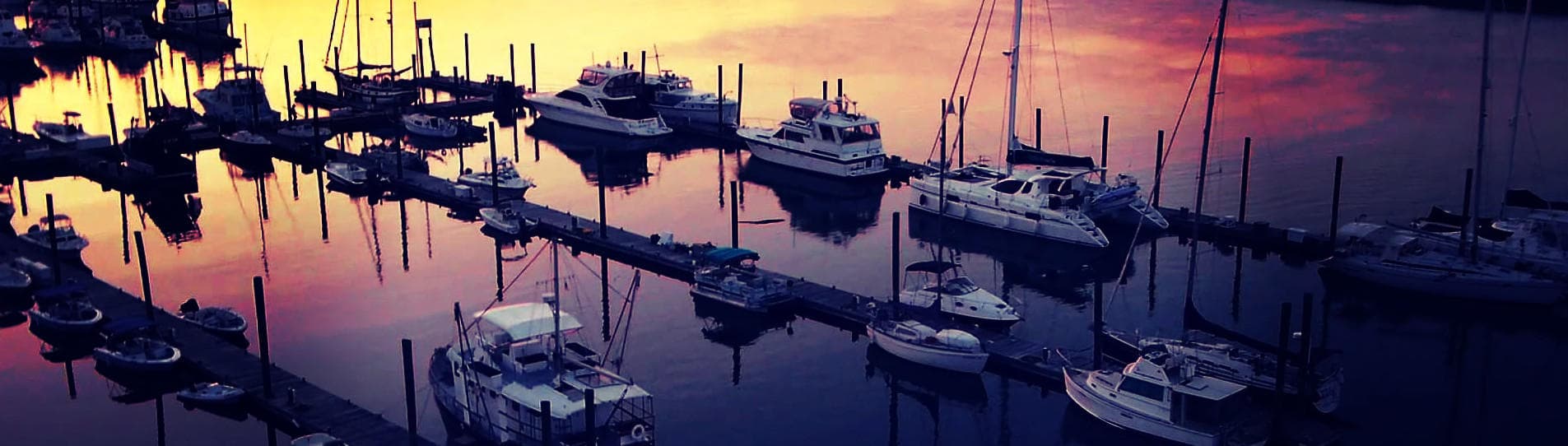 Marina sunset with anchored sailboats, coastal harbor view