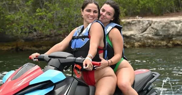 Two riders on jet ski enjoying coastal waters near rocky shore