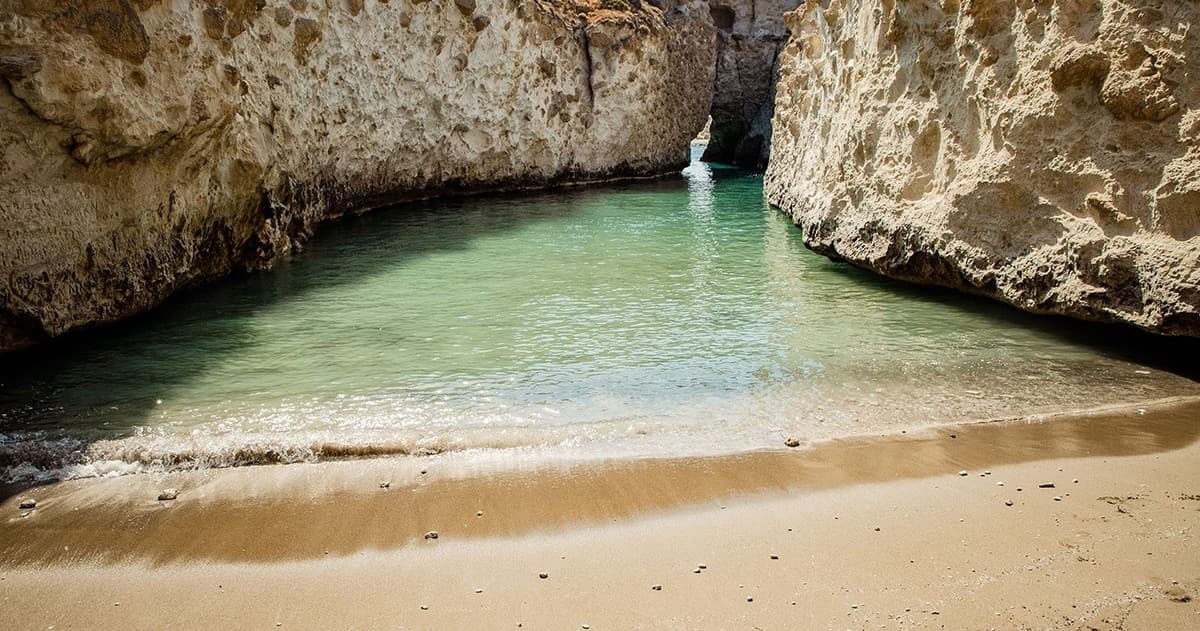 Secluded sandy cove between limestone cliffs, beach exploration