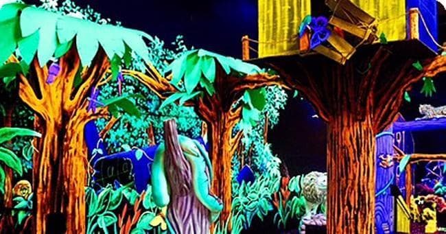 Glow-in-the-dark indoor mini golf with neon forest mural