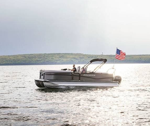 Pontoon cruising with American flag on bright open lake waters