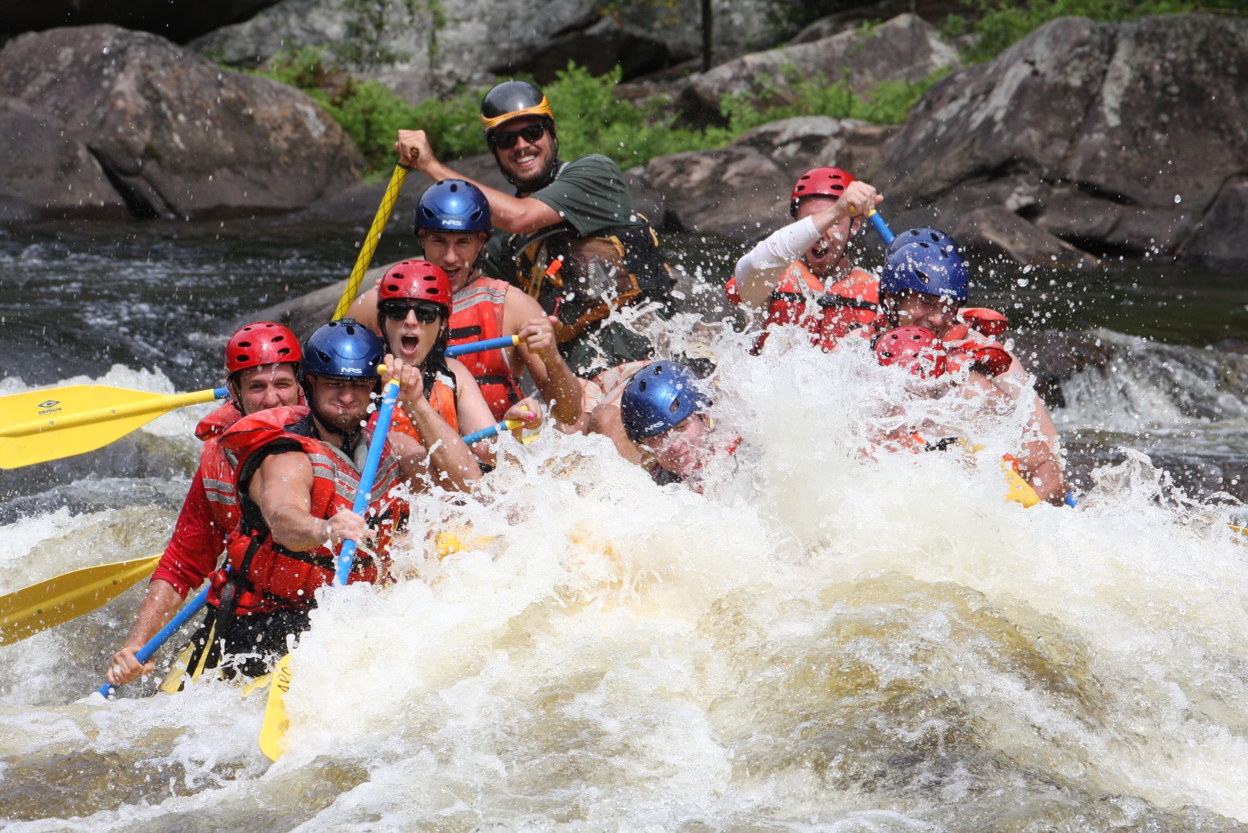 Whitewater rafters navigating turbulent river rapids amid rocks