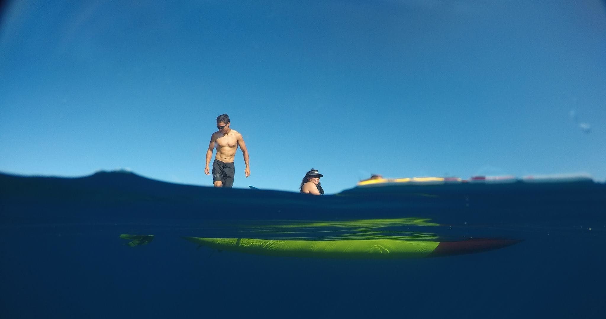 Split-level ocean shot of paddleboarder and kayak in Hawaiian sea