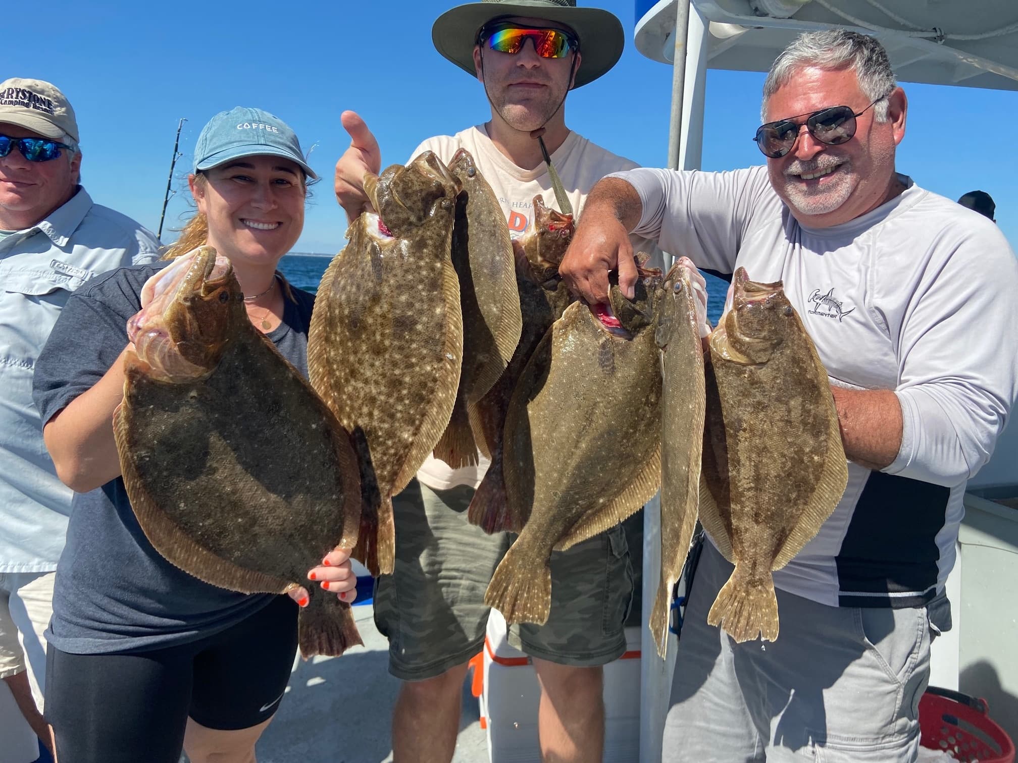 Group of anglers holding flounder on deck during charter trip