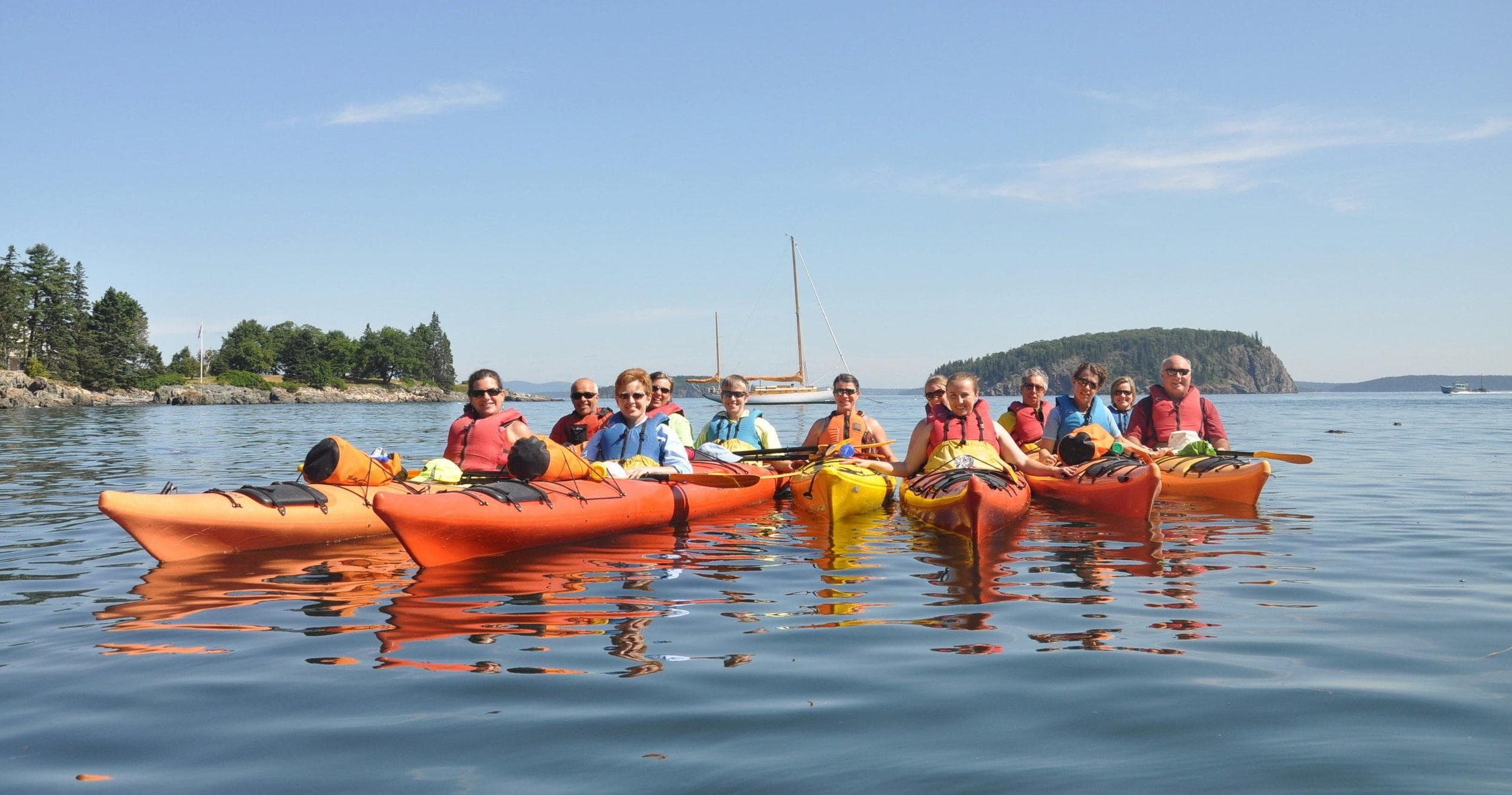Group sea kayaking on calm ocean near rocky coastline