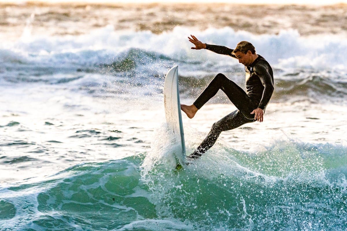 Surfer launching aerial trick over green breaking ocean wave