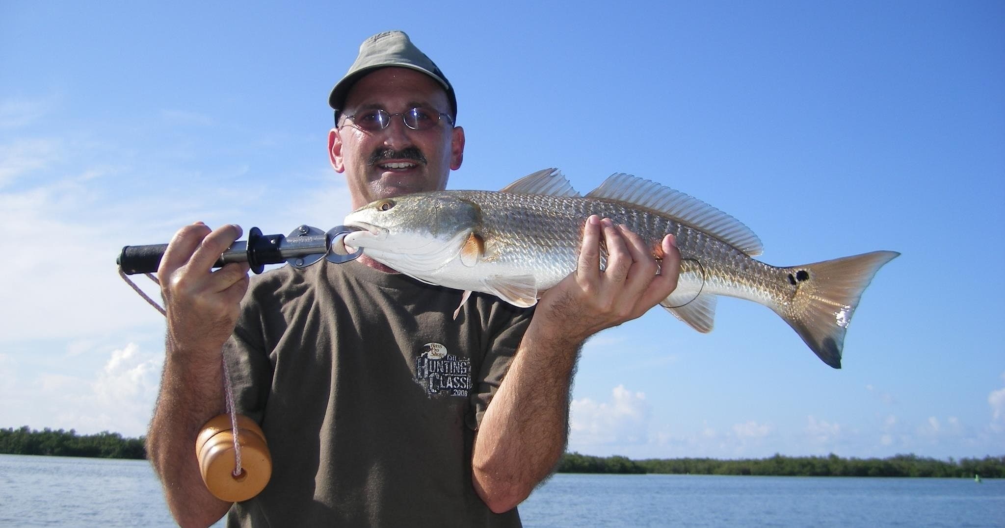 Fisherman holding redfish on charter boat with clear blue sky