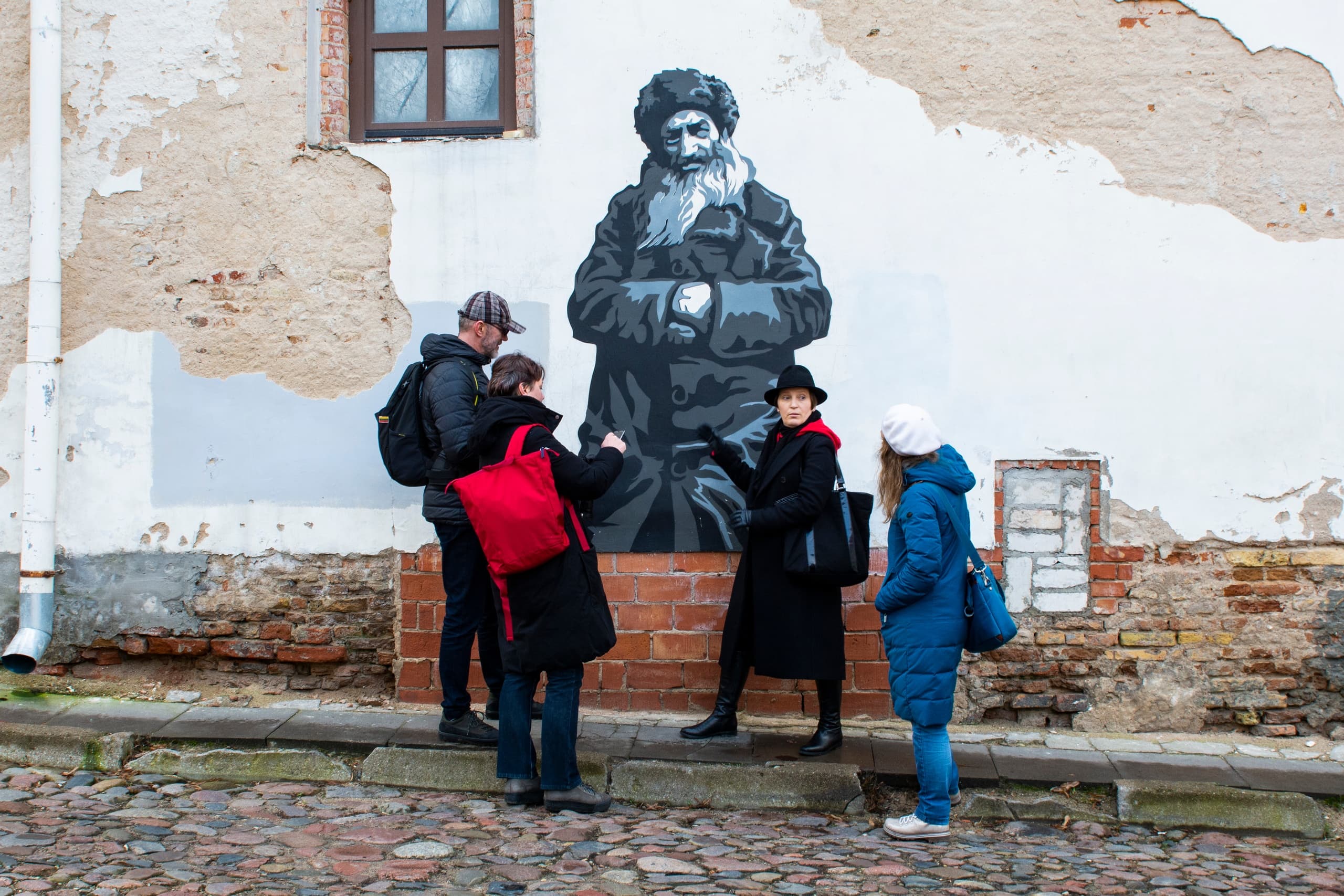 Guided walking tour by mural on cobblestone street in Baltic town