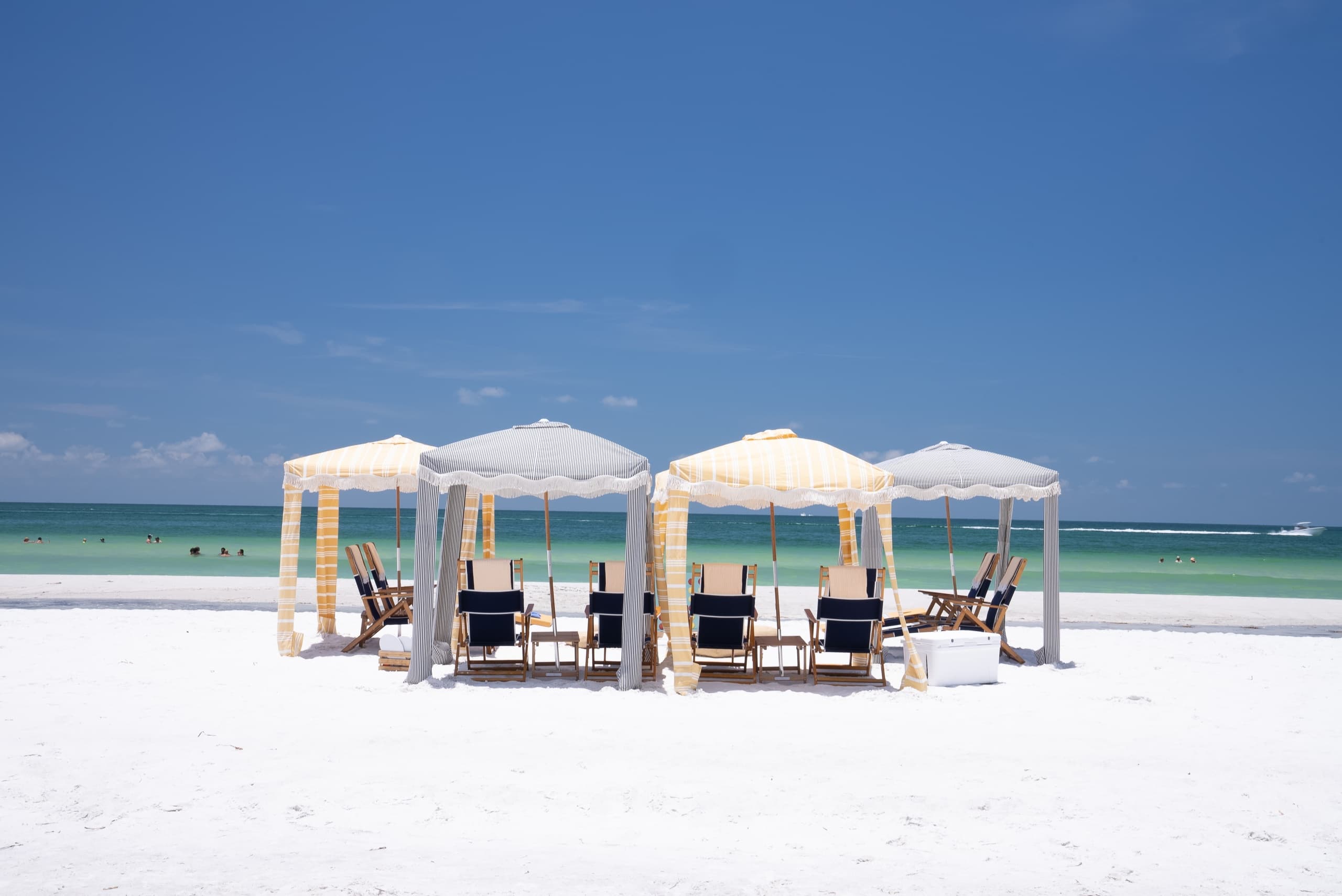 White beachfront cabanas and lounge seating under clear blue sky