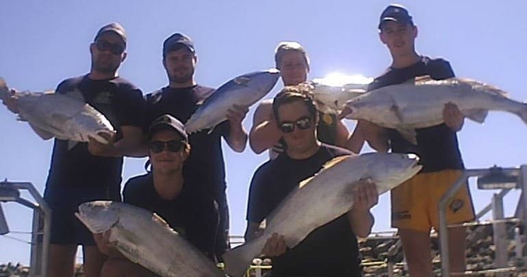 Proud anglers displaying big catches on boat deck in sunlight