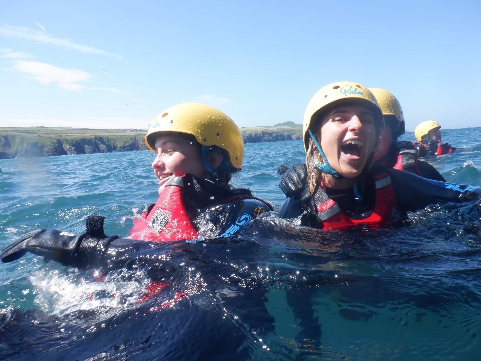 Two swimmers in helmets enjoying coastal sea swimming