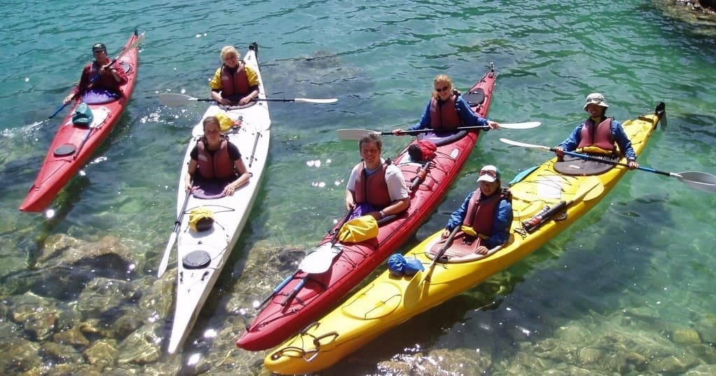Group of colorful sea kayaks in shallow crystal-clear water