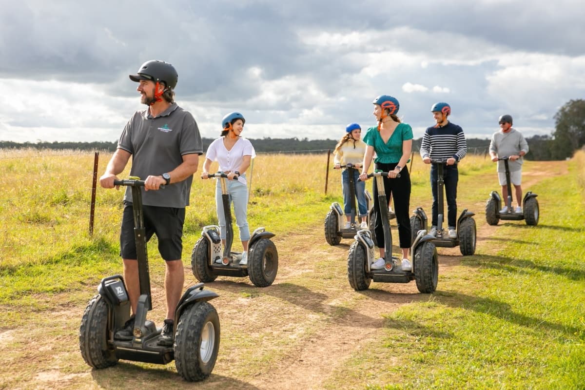 Segway tour riders cruising across grassy countryside trail