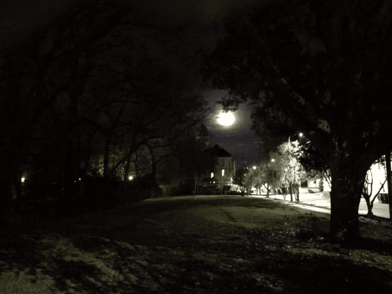 Full moon over cemetery monument during guided night ghost tour