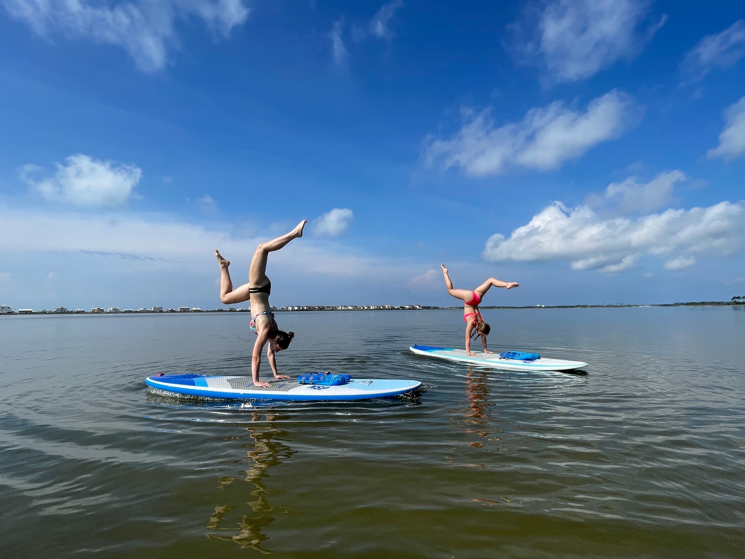 Two paddleboarders doing handstands over Dauphin Island bay