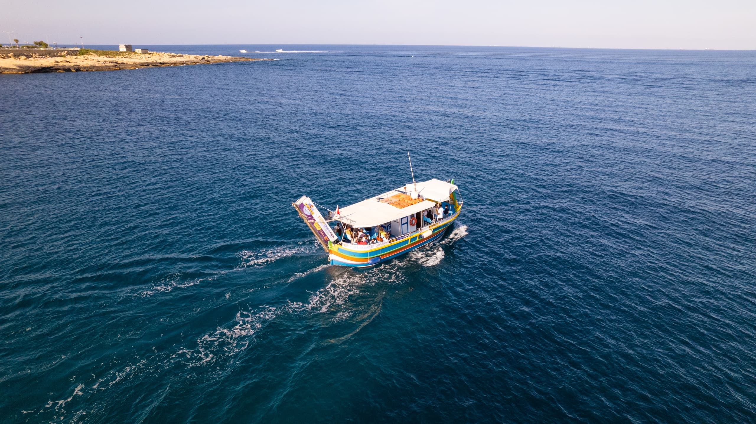 Small tour boat cruising open Mediterranean sea, aerial view