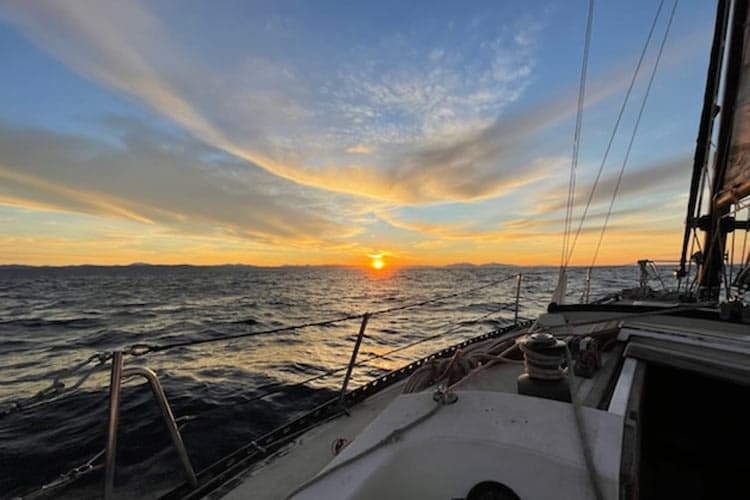 Sunset sail over open ocean with dramatic sky from sailboat deck