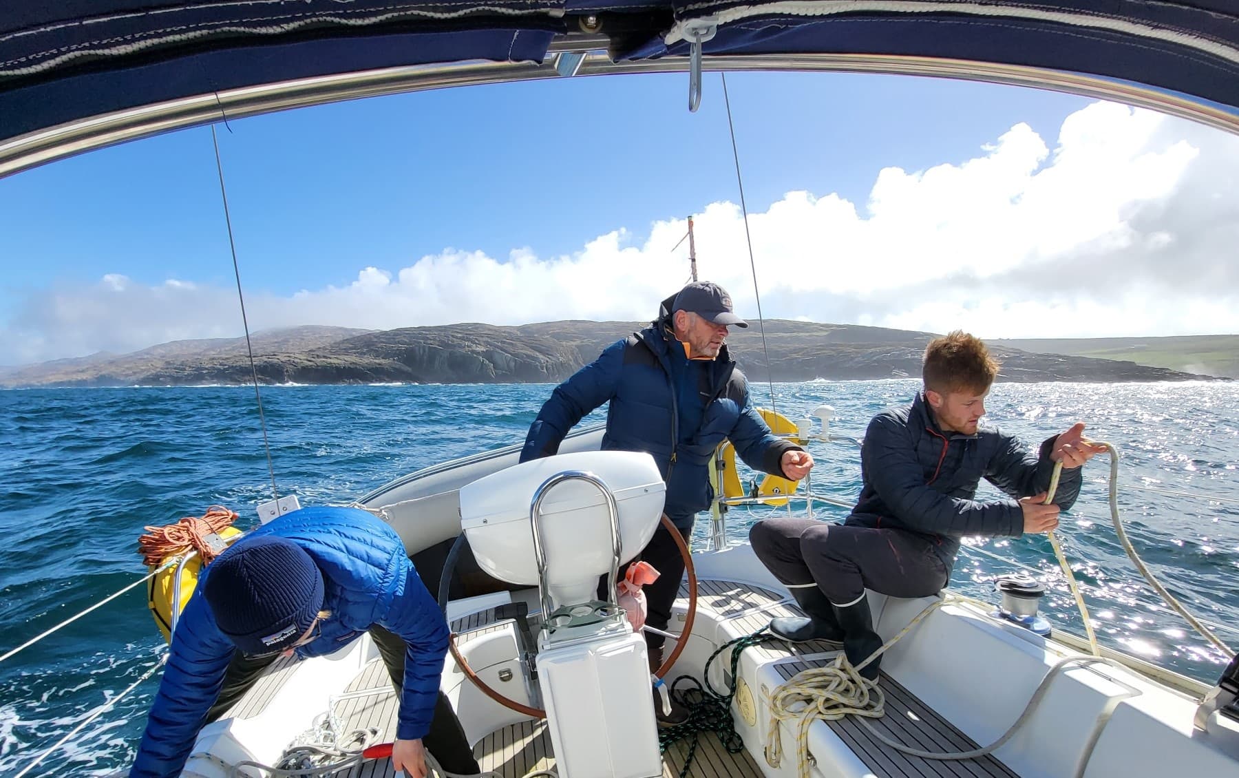 Sailing crew trimming lines on a yacht in open ocean waters
