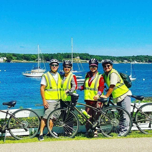 Bicyclists on grassy headland overlooking blue ocean