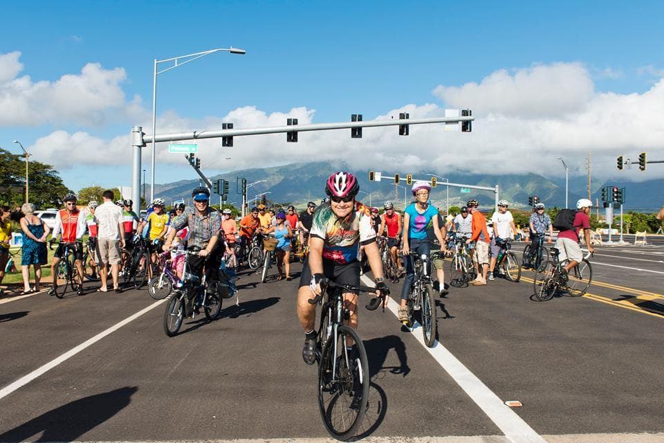 Cyclists starting urban Maui road ride at intersection on sunny day