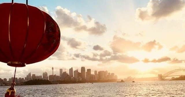 Sunset harbor cruise view of Sydney skyline and red lantern.