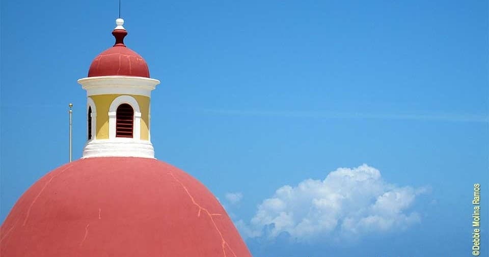 Red domed church rooftop against blue sky, panoramic city view