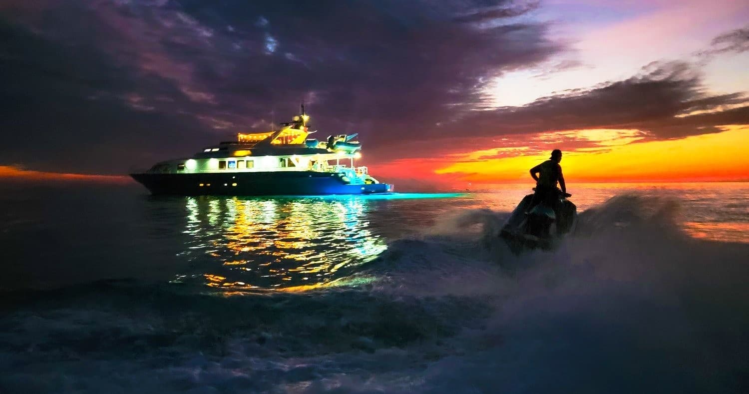 Yacht and jet ski at sunset with dramatic ocean sky