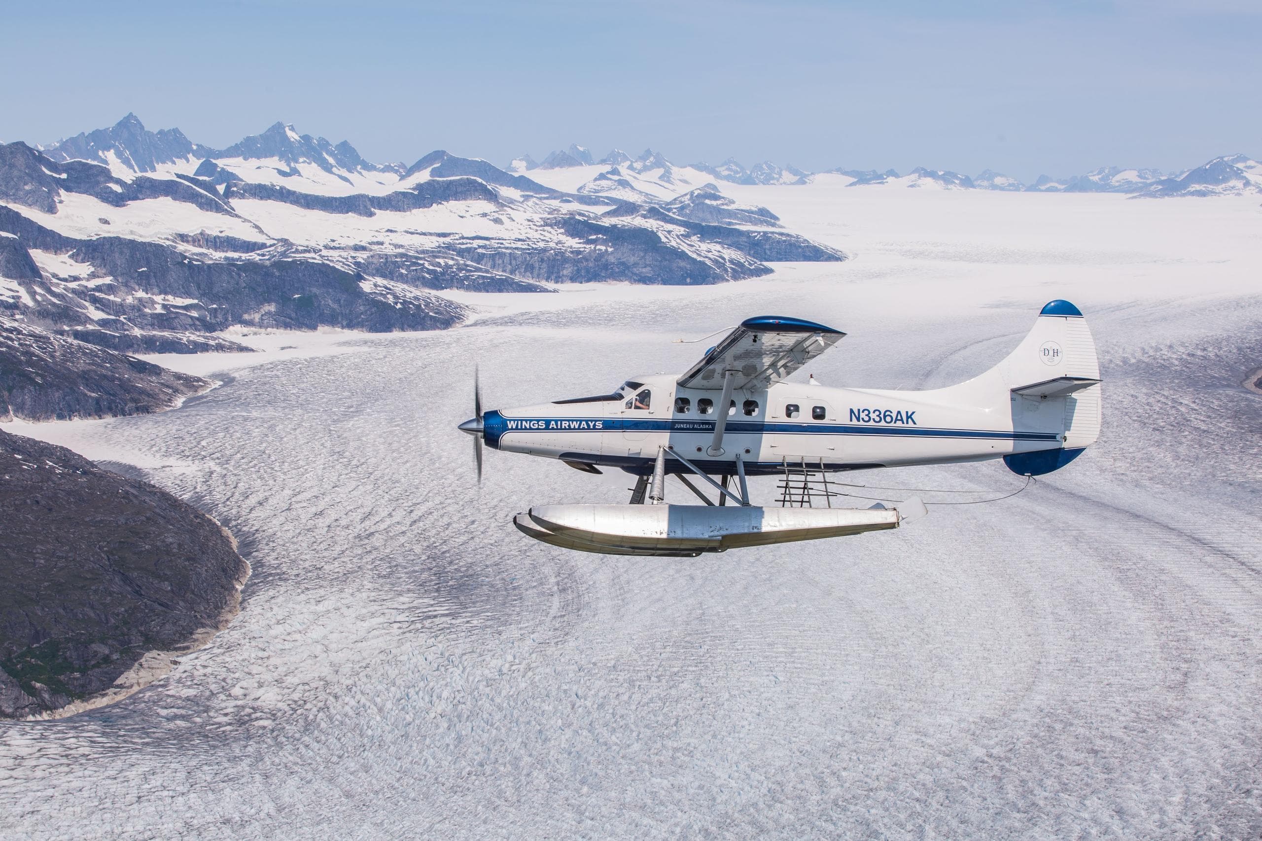 Floatplane flying over glacial icefield and mountain peaks in Alaska