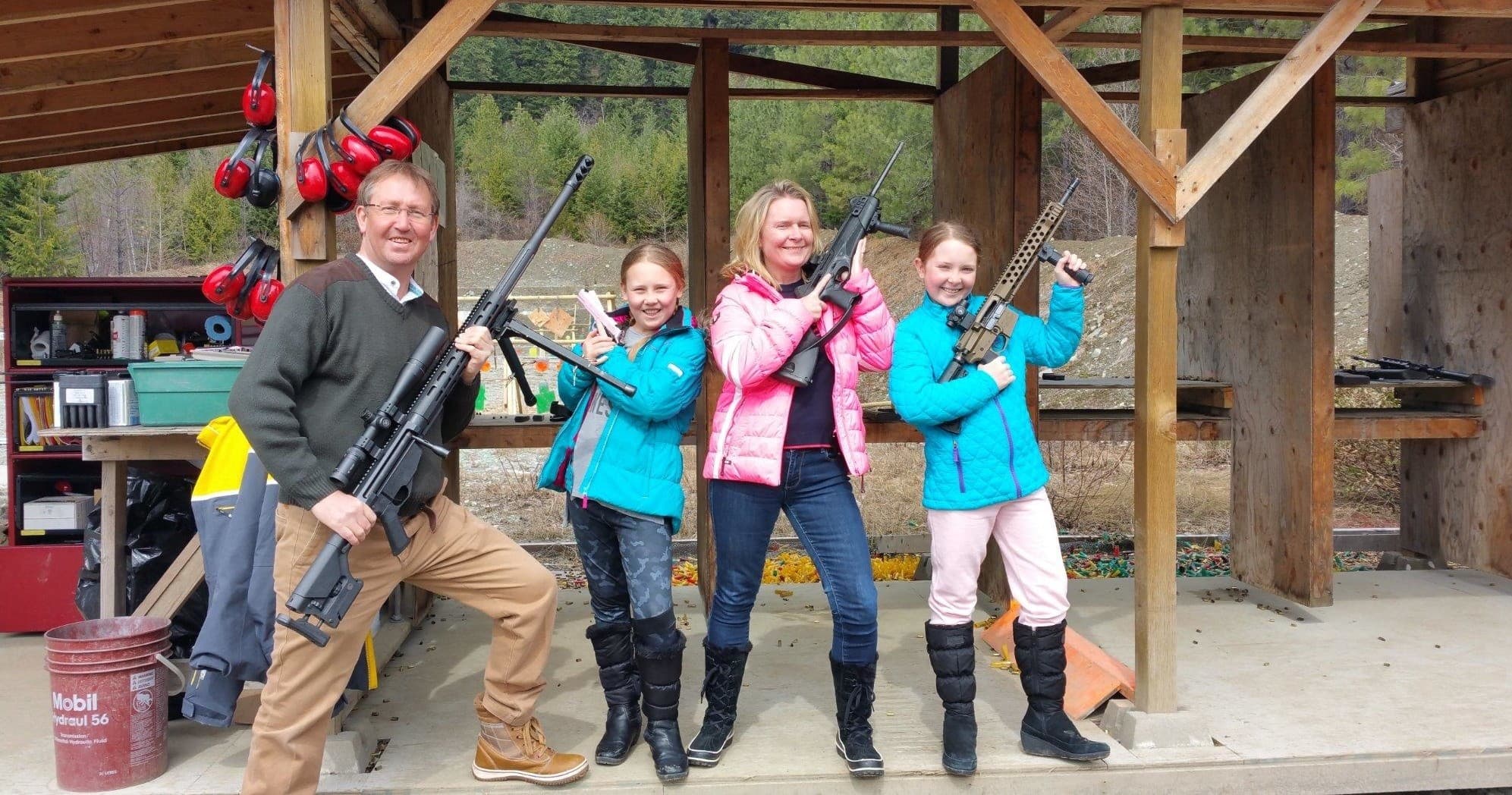 Family posing with rifles at covered outdoor shooting range