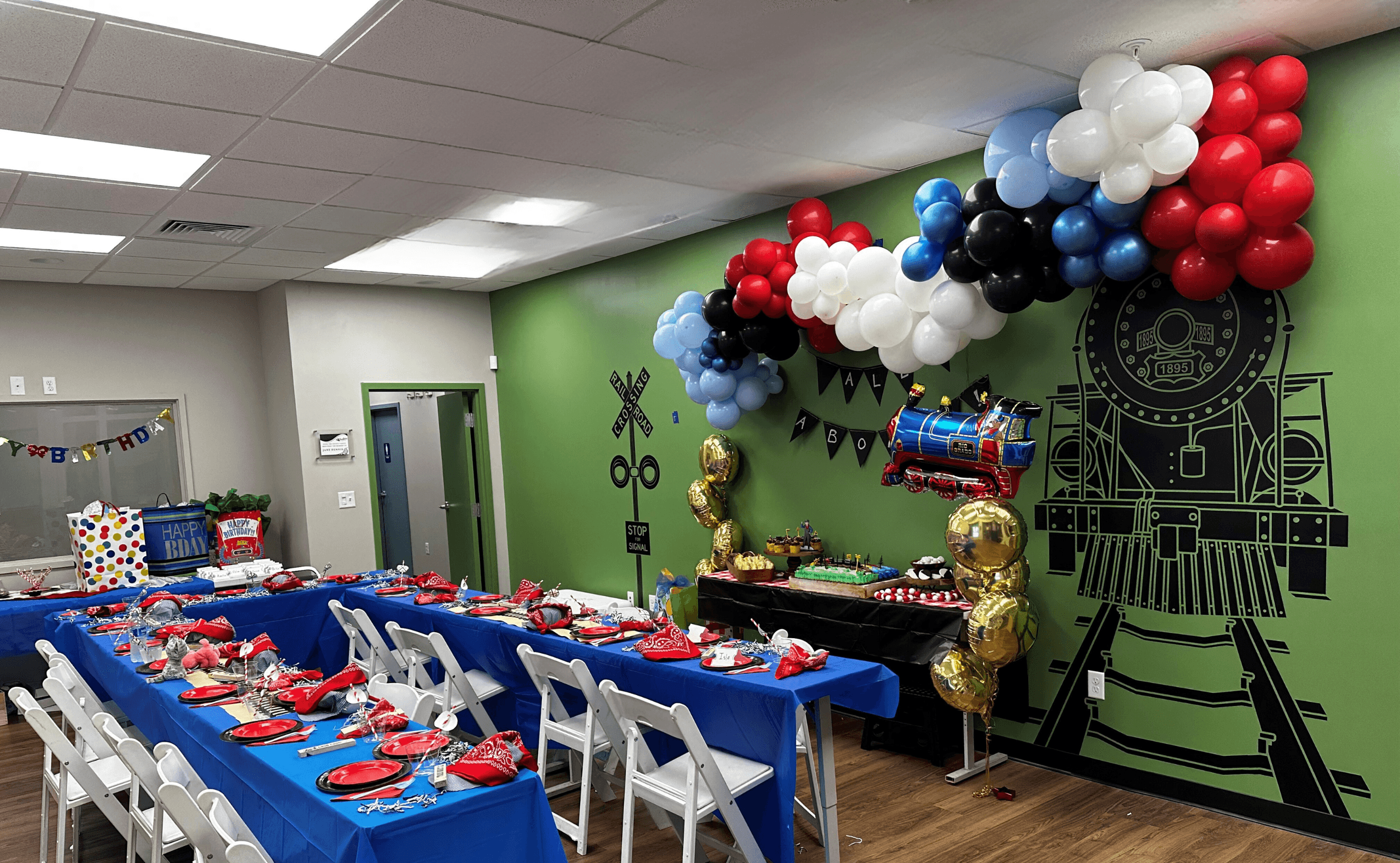 Train-themed children's party tables and balloon decor in venue