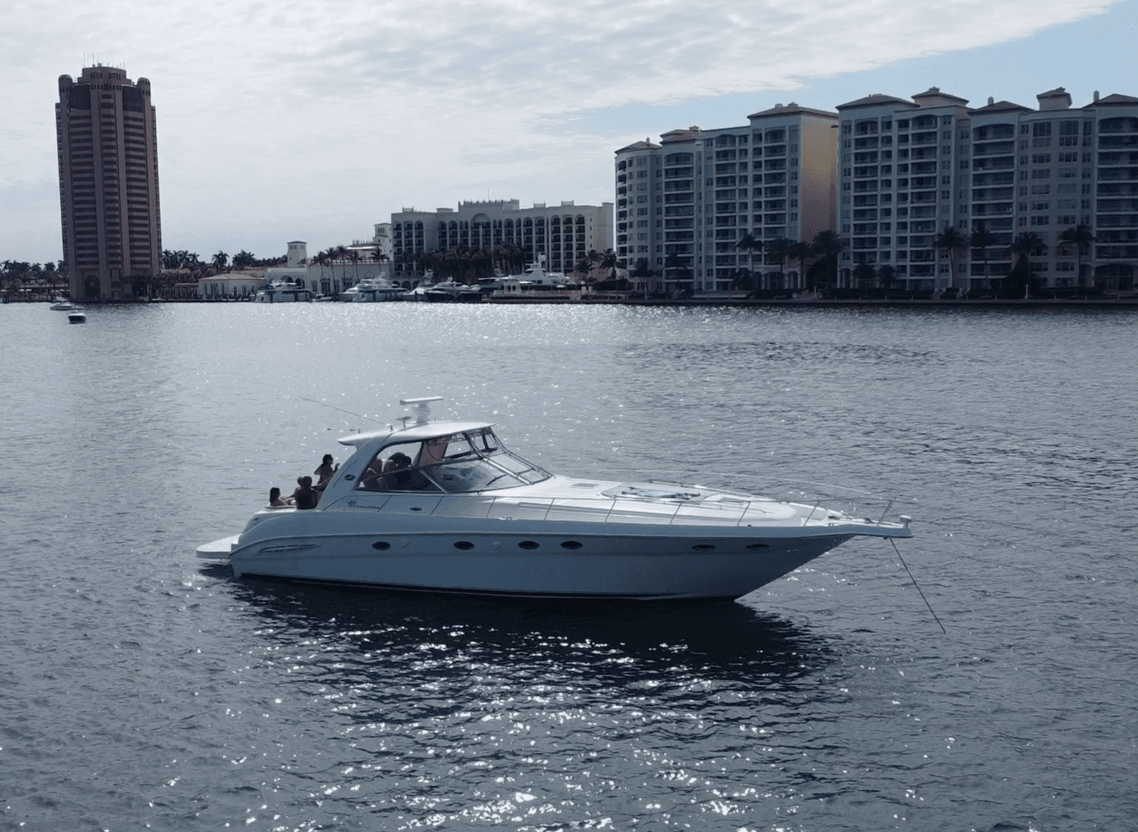 Motor yacht cruising in coastal harbor near waterfront condos