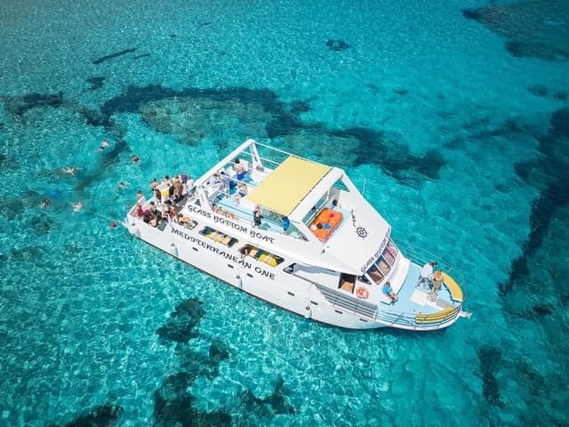Aerial view of tour boat over vivid shallow Mediterranean waters