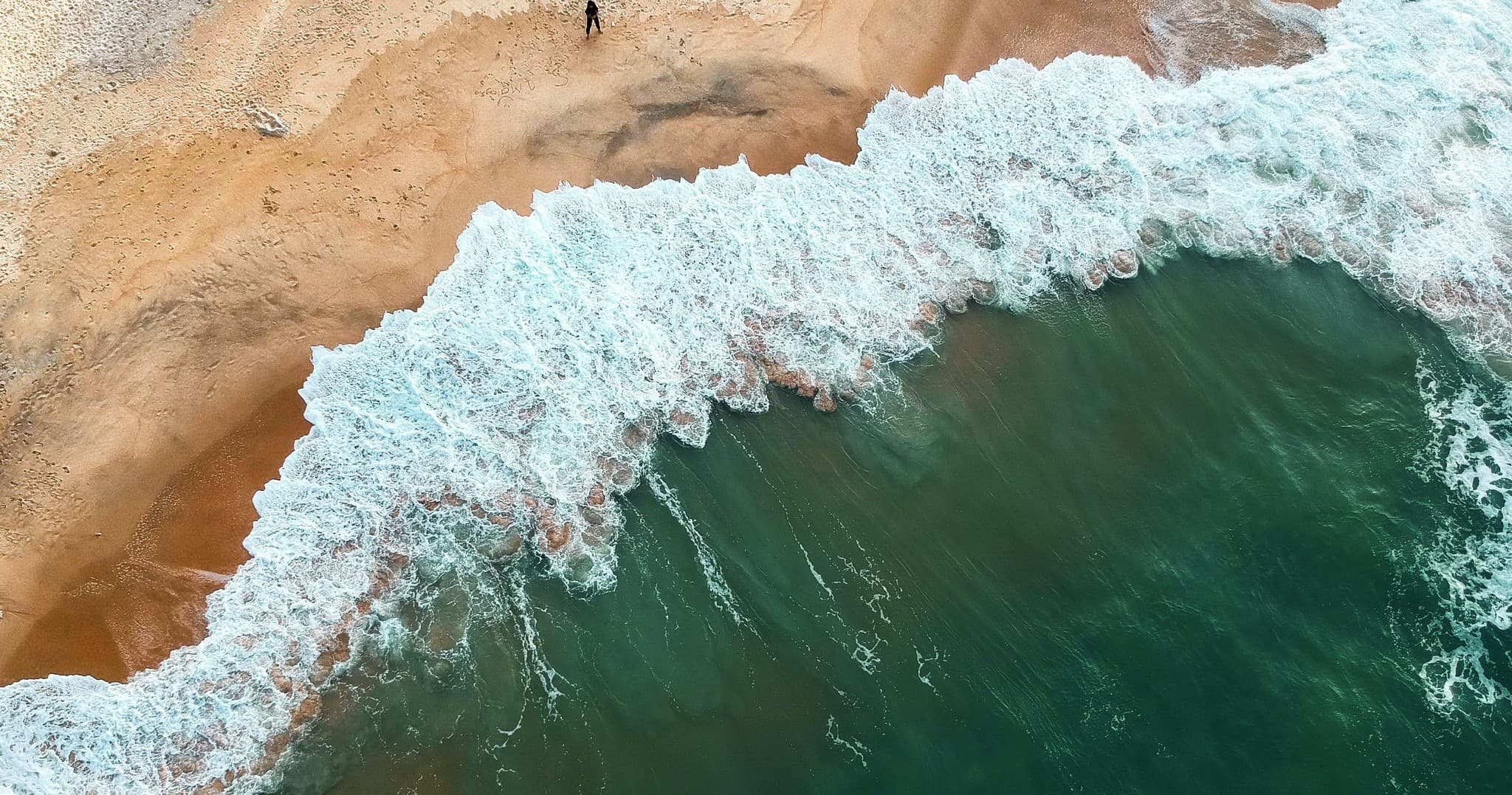 Aerial beachscape showing waves breaking on sandy shoreline