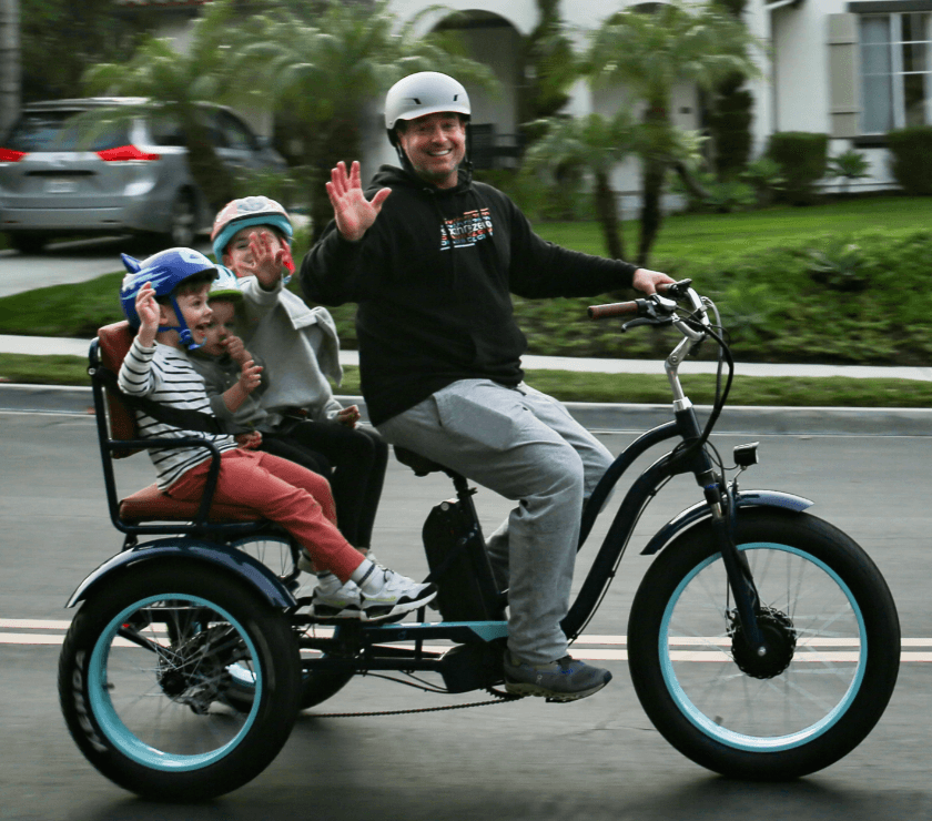 Family riding electric trike together on coastal street adventure