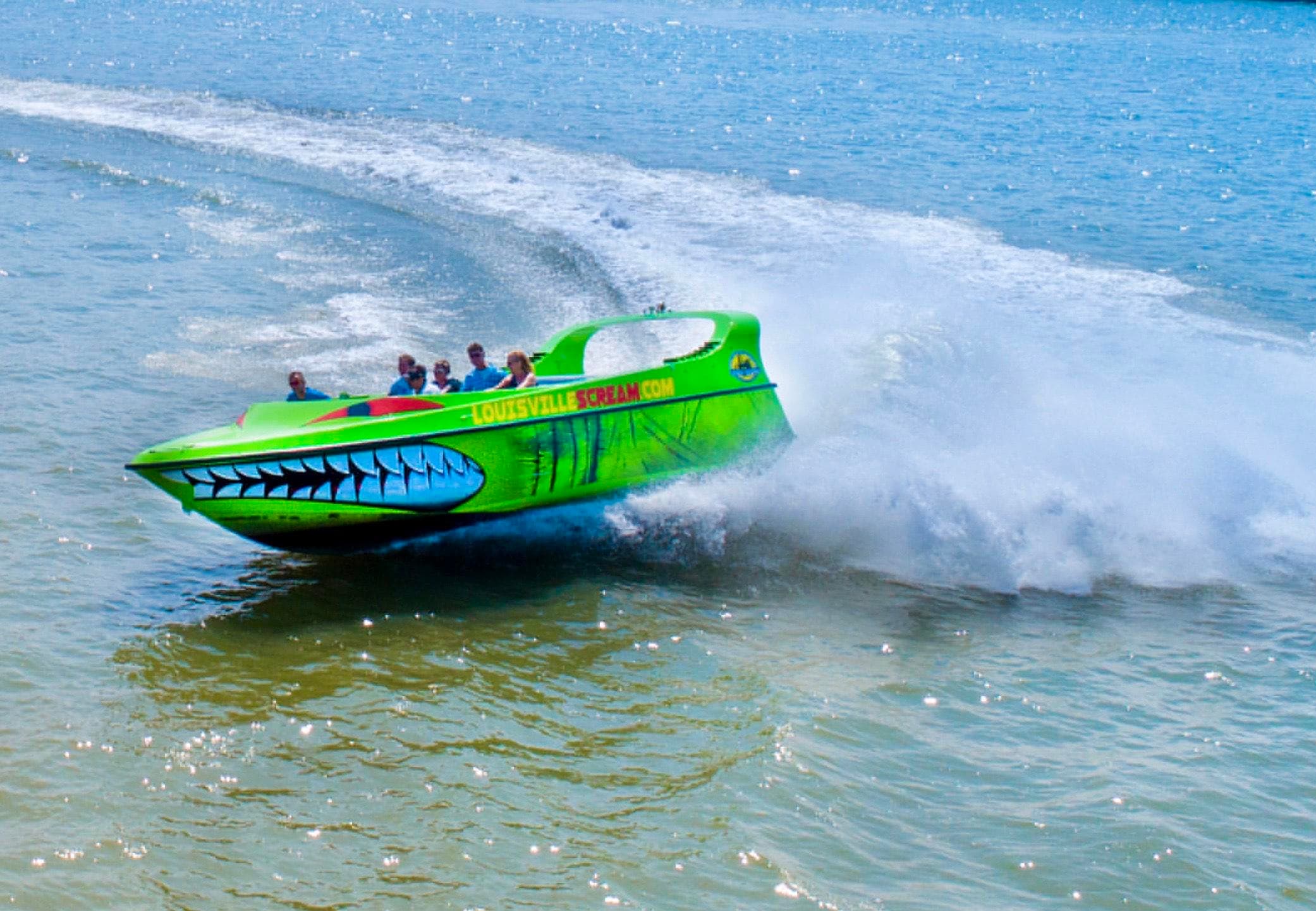 High-speed green powerboat racing across turquoise coastal water