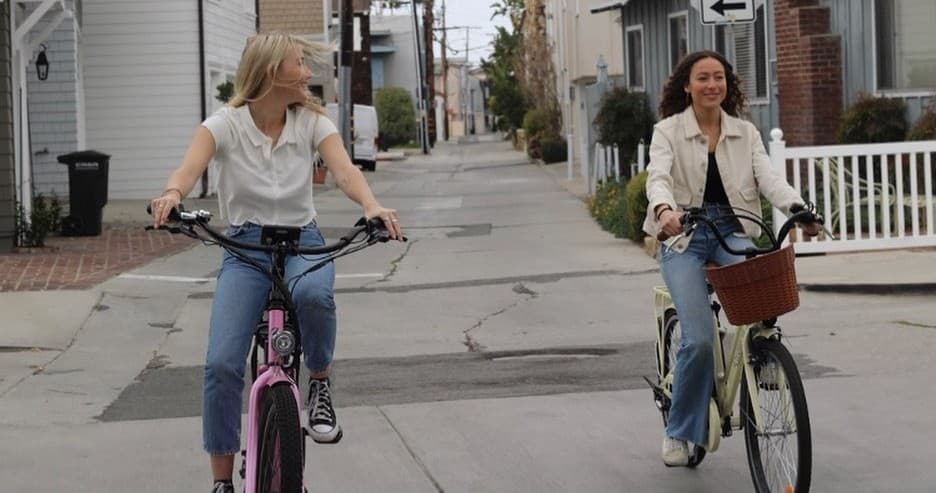 Two women biking down quiet neighborhood alley on casual ride