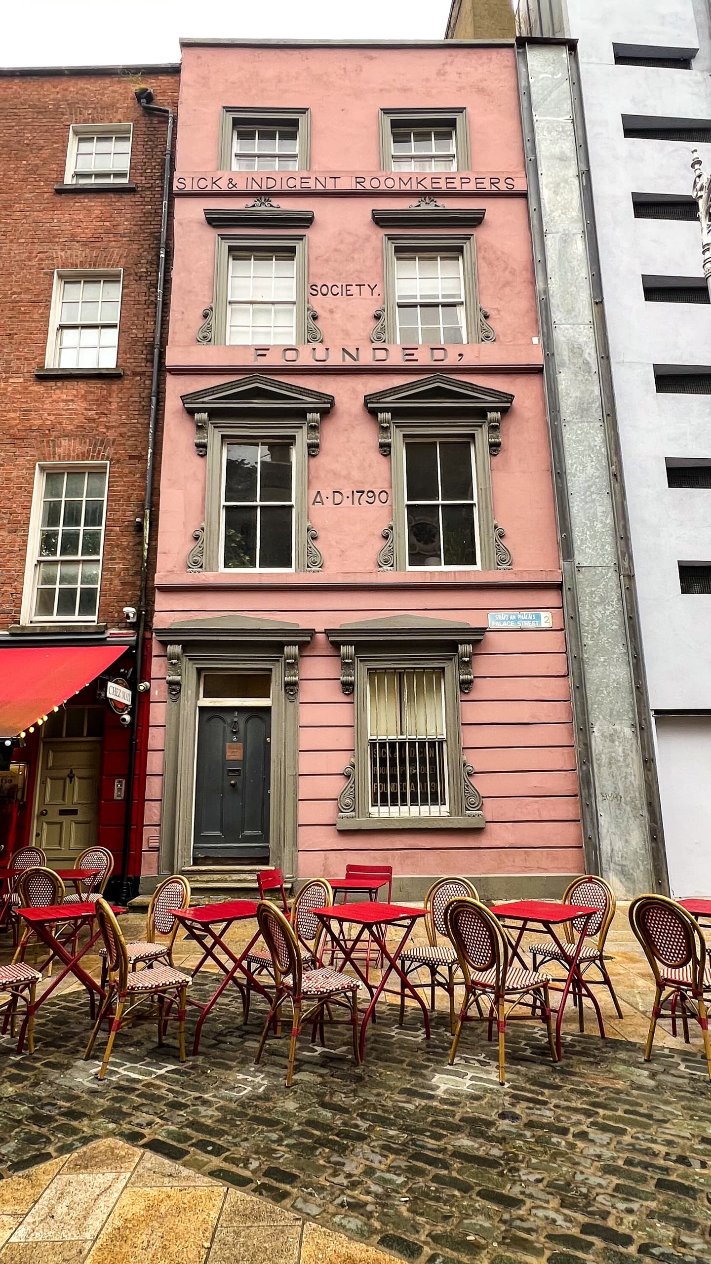 Cobblestone street cafe outside a pastel Georgian building in city