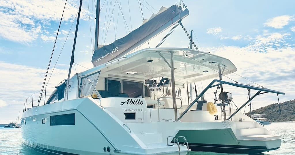 Luxury catamaran anchored in calm bay under blue sky, sailing