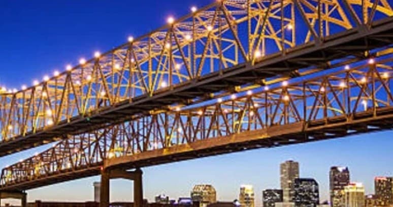 Suspended bridge lit at dusk over city skyline, urban night view