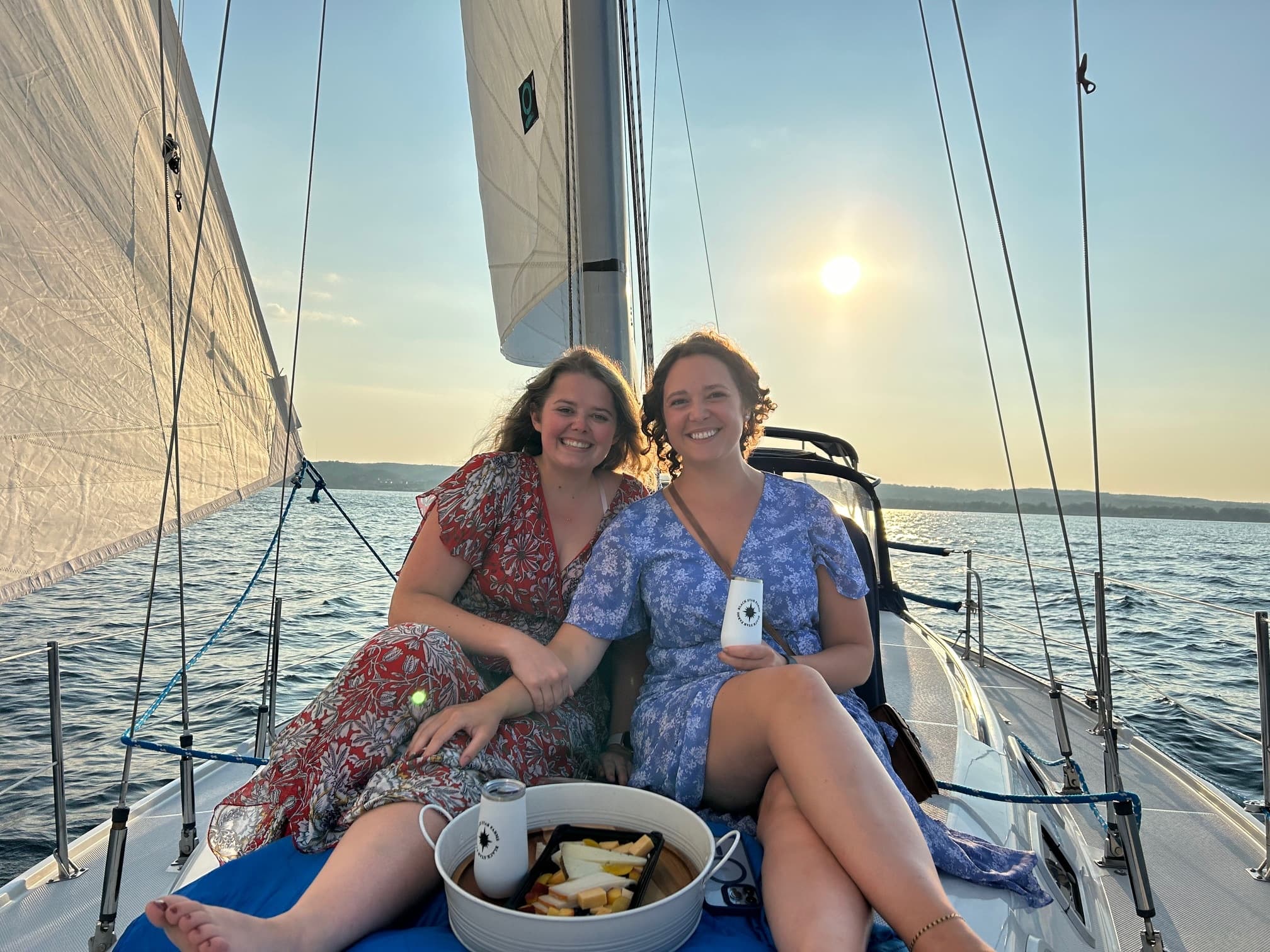 Two friends relaxing on sailboat deck at sunset, leisure sailing