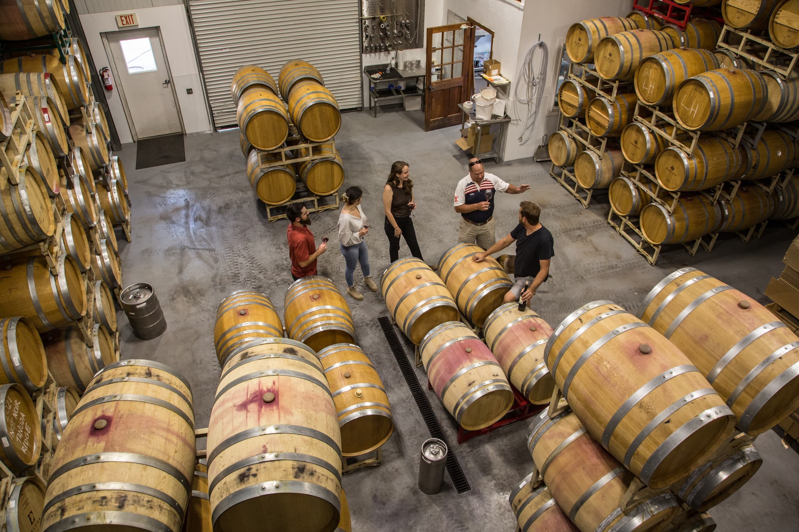 Winery barrel aging room tour with staff inspecting oak casks