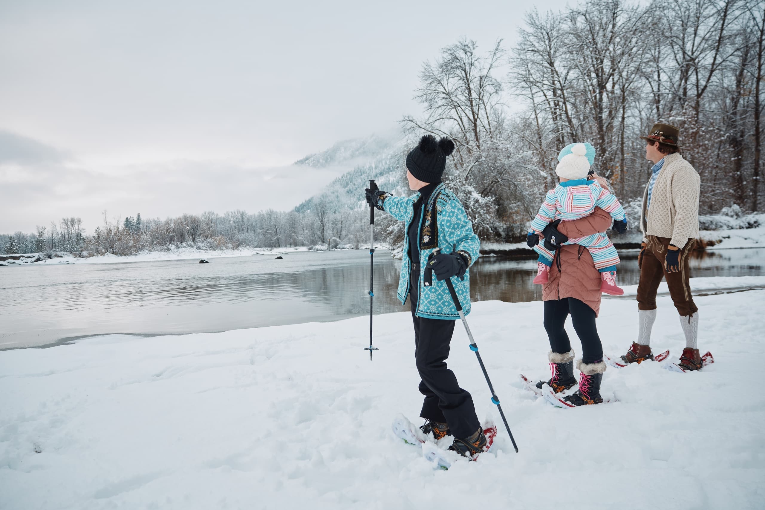 Snowshoers trekking by frozen lake in alpine winter landscape