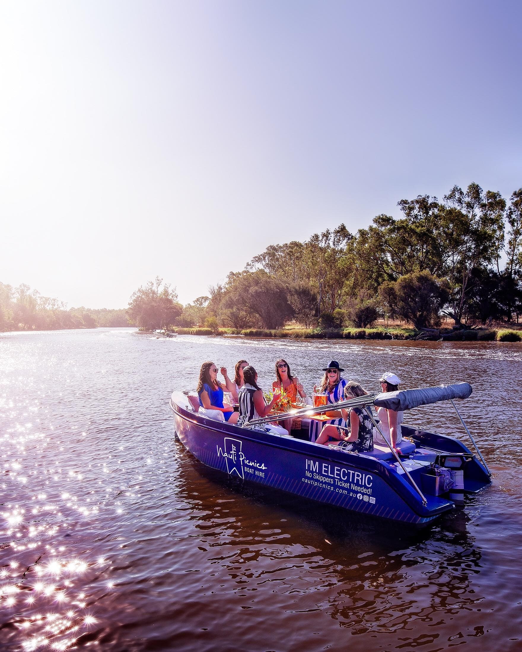 Electric picnic boat carrying guests on sunlit river cruise