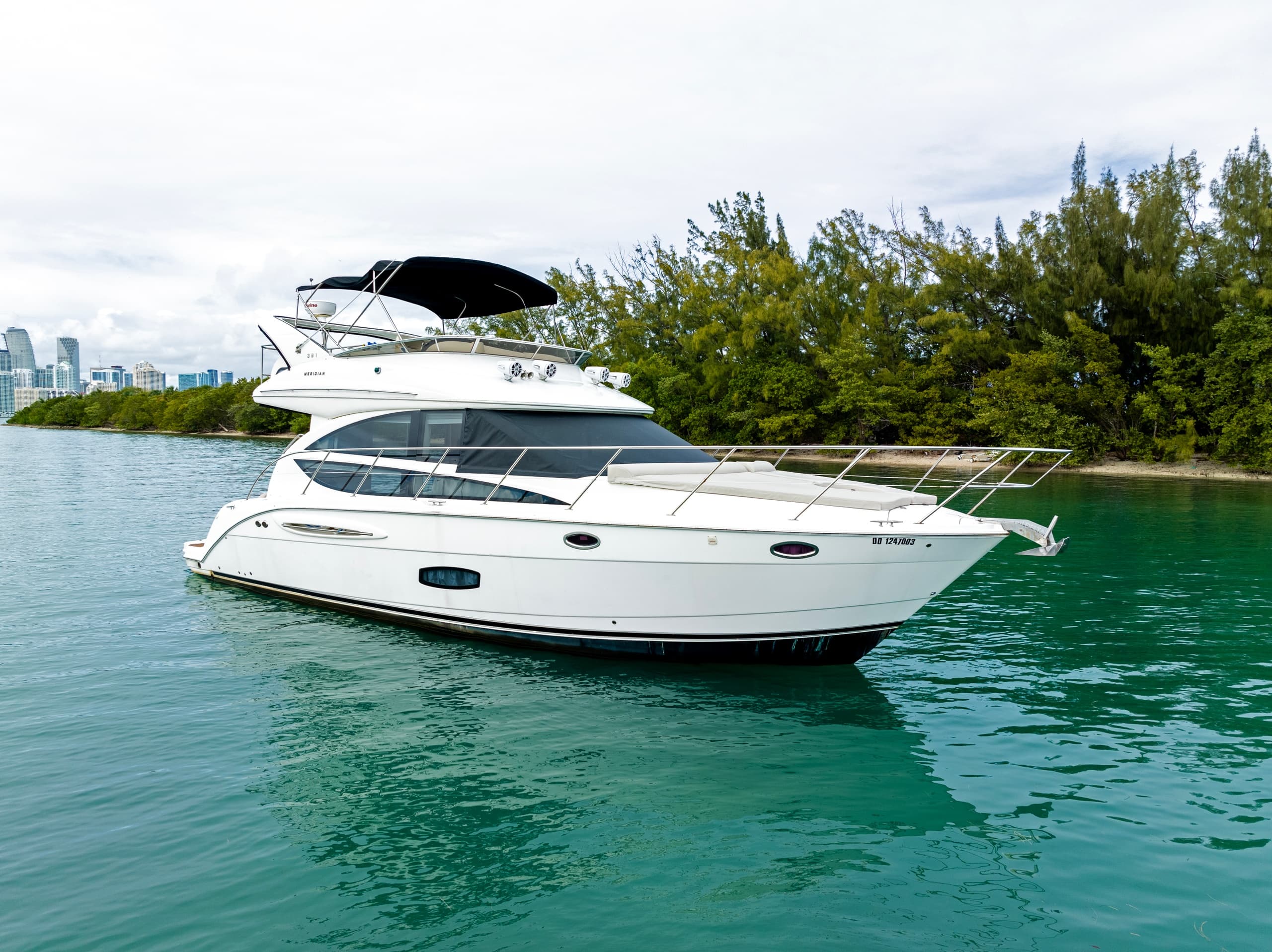 Two-deck motor yacht cruising calm green coastal waters, sunny