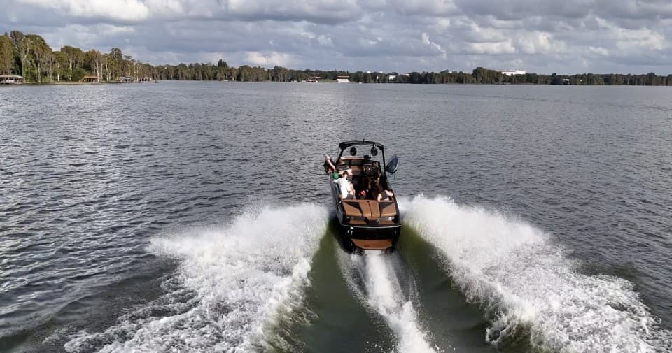 Motorboat creating large wake on scenic lake for watersports