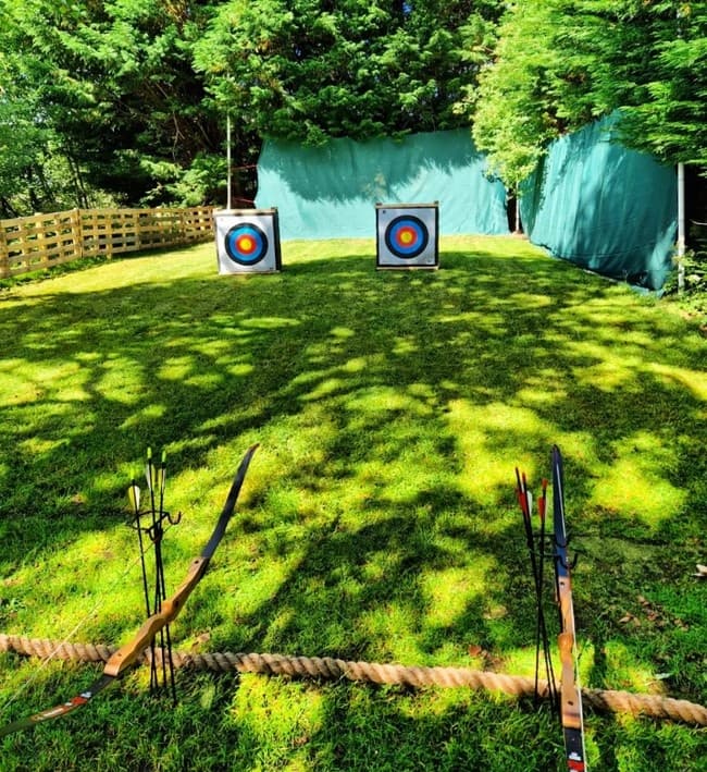 Archery targets and bows on sunlit grassy outdoor range