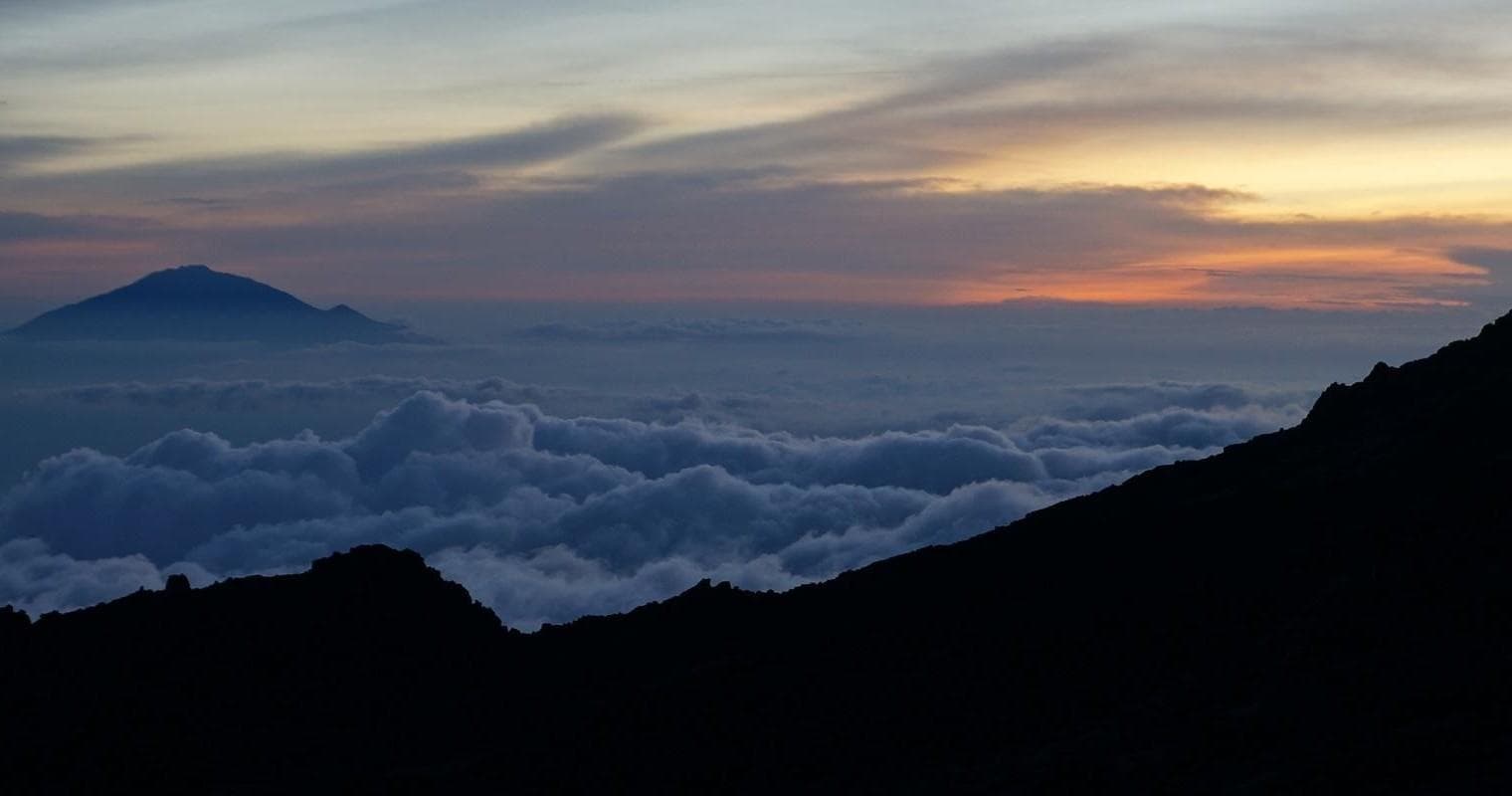 Sunrise over cloud inversion and silhouette ridge, mountain sunrise trek