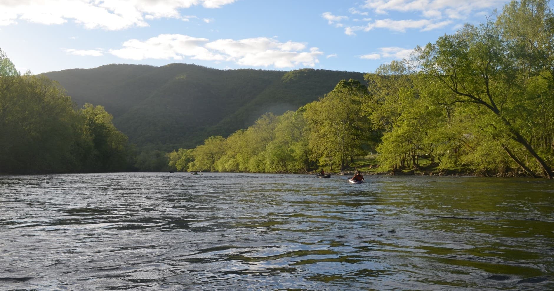 Paddlers on a wide river valley with distant mountains, scenic view