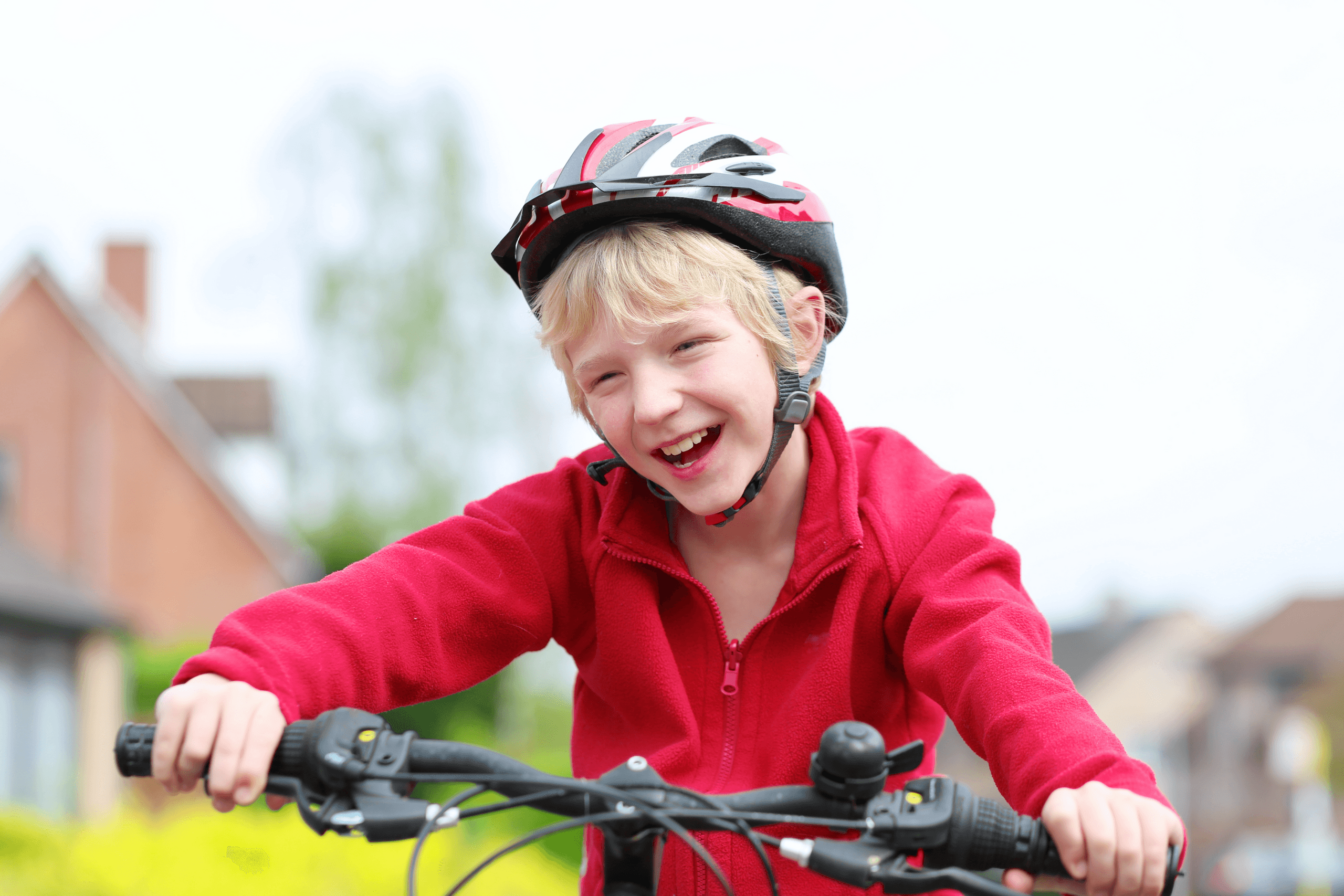 Child cycling on neighborhood street wearing helmet, smiling